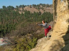 Woman facing the sun on a mountain, dressed in Indian pants, practicing yoga, portrait on an autumn day photo