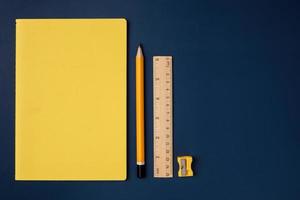 top view pastel yellow notebook with yellow pencil and notepad on navy blue working table photo