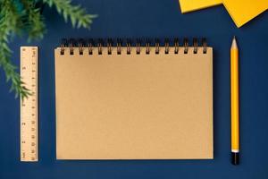 top view brown notebook with yellow pencil and notepad on navy blue working table photo