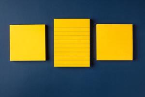 blank yellow sticky note on navy blue table background photo