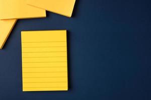 blank yellow sticky note on navy blue table background photo