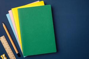 top view pastel notebook with yellow pencil and notepad on navy blue working table photo