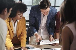 El equipo y los colegas multirraciales de los compañeros de trabajo intercambiaron ideas, discutieron la estrategia de marketing, la colaboración de ideas y la planificación de proyectos comerciales en la mesa de conferencias de una oficina en el lugar de trabajo de la reunión del personal. foto