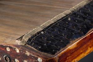 ancient Asian stringed musical instrument on black background with backlight. the similarity of the harp and psaltery. closeup photo