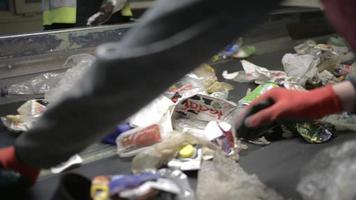 arbeidershanden die plastic afval sorteren dat zich op transportband, afvalsorteerstation beweegt; video