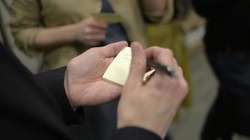 personnes enregistrant des notes sur un bloc-notes lors d'une conférence au bureau video