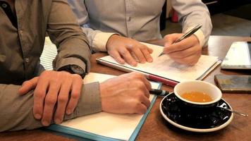 twee zakenlieden plannen werk met pen en papier op een lunch in café video
