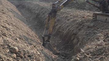 graaflaadmachine, graafmachine die een greppel graaft. klem. werk van het opgraven van de machine op de bouwplaats. graafmachine graaft een gat 4k shot video