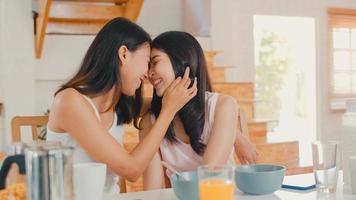 Asian Lesbian lgbtq women couple have breakfast at home, Young Asia lover female feeling happy drink juice, corn flakes cereal and milk in bowl on table in kitchen in the morning concept. photo