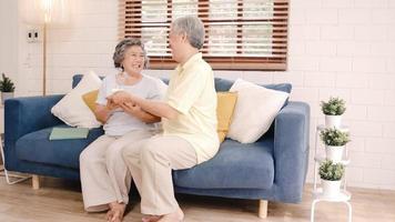 Asian elderly couple man holding cake celebrating wife's birthday in living room at home. Japanese couple enjoy love moment together at home. Lifestyle senior family at home concept. photo