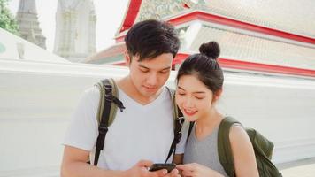 Traveler Asian couple direction on location map in Bangkok, Thailand, couple using mobile phone looking on map find landmark while spending holiday trip. Lifestyle couple travel in city concept. photo