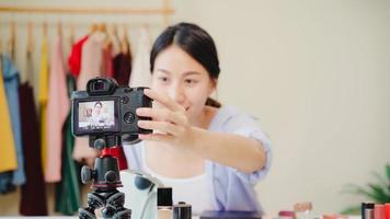 Beauty blogger present beauty cosmetics sitting in front camera for recording video. Beautiful asian woman use cosmetics review make up tutorial broadcast live video to social network by internet. photo