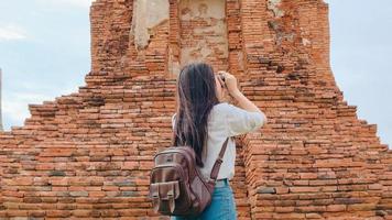 Traveler Asian woman using camera for take a picture while spending holiday trip at Ayutthaya, Thailand, Japanese female tourist enjoy her journey at amazing landmark in traditional city. photo