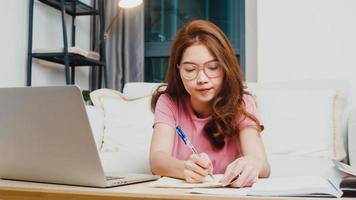 Lección de aprendizaje a distancia de una joven estudiante adolescente de Asia con un maestro en línea y estudio en una computadora portátil en la sala de estar de casa por la noche. distanciamiento social, cuarentena para la prevención del virus de la corona. foto