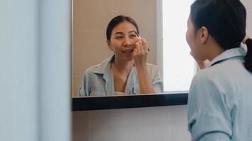 Beautiful Asian woman using eyebrow pencil make up in front mirror, Happy latin female using beauty cosmetics to improve herself ready to working in bathroom at home. Lifestyle women relax at home. photo