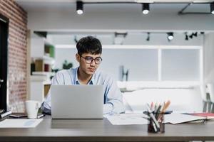 Asian creative man drawing work plan on paper board. Young professional business male think and write information reminder on paper on brick, business situation, startup in Loft office concept. photo