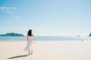 Beautiful young Asian woman happy relax walking on beach near sea. Lifestyle women travel on beach concept. photo