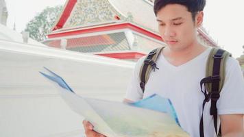 Traveler Asian man direction on location map in Bangkok, Thailand, backpacker male looking on map find landmark while spending holiday trip. Lifestyle men travel in Asia city concept. photo