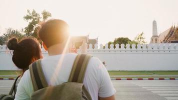 Traveler Asian couple using mobile phone for take a picture while spending holiday trip at Bangkok, Thailand, couple enjoy journey at landmark in sunset. Lifestyle couple travel in city concept. photo