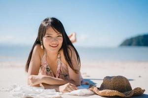 Beautiful Young Asian woman lying on beach happy relax near sea. Lifestyle women travel on beach concept. photo