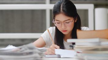 Asian student women reading books in library at university. Young undergraduate girl do homework, read textbook, study hard for knowledge and education on lecture desk at college campus. photo