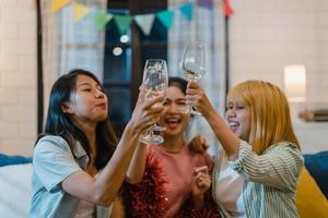 grupo de mujeres asiáticas de fiesta en casa, mujeres bebiendo cócteles hablando divertidas juntas en el sofá en la sala de estar por la noche. adolescente joven amigo jugar juego, amistad, celebrar el concepto de vacaciones. foto