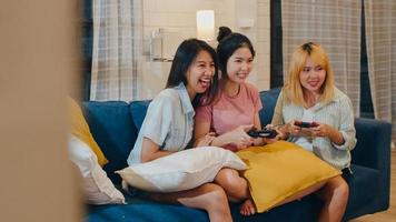 Group of Asian women couple play games at home, female using joystick having funny moment together on sofa in living room in night. Teenager young friend football fan, celebrate holiday concept. photo