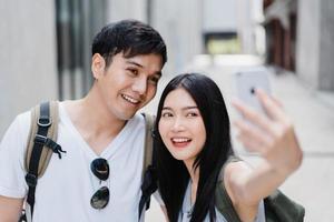 Asian blogger couple travel in Beijing, China, sweet couple using mobile phone selfie photo view while spending sweet time in holiday trip. Couple travel in city concept.