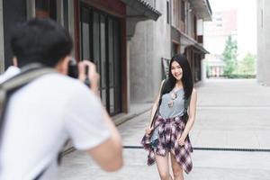 Traveler Asian couple travel in Beijing, China, sweet couple using camera taking photo each other near street while spending holiday trip. Lifestyle couple travel in city concept.