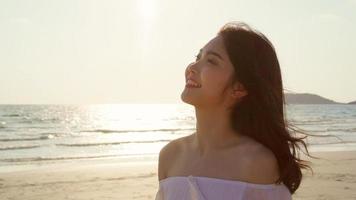 Young Asian woman walking on beach. Beautiful female happy relax walking on beach near sea when sunset in evening. Lifestyle women travel on beach concept. photo