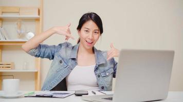 Young asian woman working using laptop on desk in living room at home. Asia business woman success celebration feeling happy dancing at home office. Enjoying time at home concept. photo