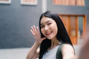 Asian blogger woman travel in Beijing, China, backpacker female using mobile phone make vlog and live in social media while spending sweet time in holiday trip. Women travel in city concept. photo