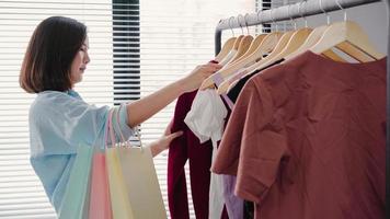 Asian woman shopping clothes. Shopper looking at clothing on the rail indoors in clothing store. Beautiful happy smiling asian woman model. Medium shot. photo