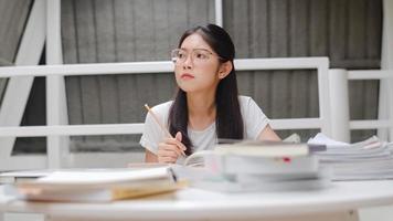 Asian student women reading books in library at university. Young undergraduate girl do homework, read textbook, study hard for knowledge and education on lecture desk at college campus. photo