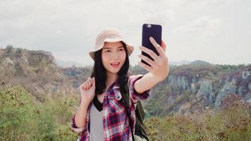 Asian backpacker woman selfie on top of mountain, young female happy using mobile phone taking selfie enjoy holidays on hiking adventure. Lifestyle women travel and relax concept. photo