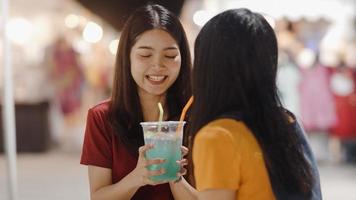 Asian young women friends travel in Bangkok, Thailand, beautiful female feeling happy drinking cocktail at The Khao San Road. Women travel eat street food in Thailand concept. photo