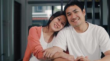 Portrait young Asian Pregnant couple relax toothy smile looking to camera at home. Mom and Dad feeling happy funny peaceful while take care child sitting on table in living room at house in morning. photo