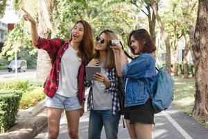 Group of Asian women using camera to make photo while traveling at park in urban city in Bangkok, Thailand. Lifestyle beautiful friends tourist travel holiday in Thailand concept.