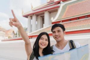 Traveler Asian couple direction on location map in Bangkok, Thailand, sweet Asia couple looking on map find landmark while spending holiday trip. Lifestyle couple travel in city concept. photo