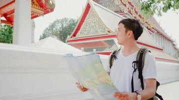 Traveler Asian man direction on location map in Bangkok, Thailand, backpacker male looking on map find landmark while spending holiday trip. Lifestyle men travel in Asia city concept. photo