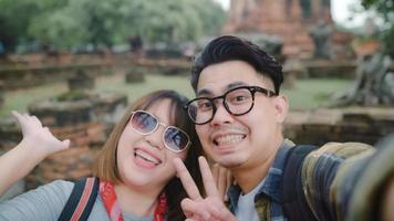 Viajero pareja asiática que usa un teléfono inteligente tomando selfie mientras pasa un viaje de vacaciones en ayutthaya, tailandia, la pareja disfruta de su viaje en un lugar increíble en la ciudad tradicional. foto