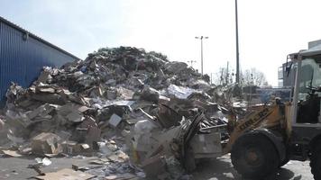 grandi escavatori afferrano i rifiuti di carta in una stazione di smistamento dei rifiuti video