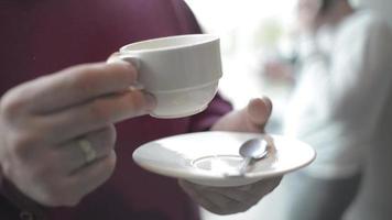 las manos del hombre de primer plano toman una taza de café en el restaurante del hotel por la mañana