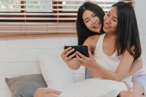 Asian influencer Lesbian lgbtq women couple vlog at home. Young Asia lover girl happy relax record vlog video to social media after wake up lying on bed in bedroom at home in the morning concept. photo