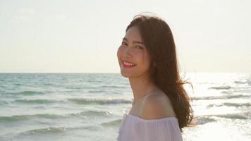 joven mujer asiática que se siente feliz en la playa, hermosa mujer feliz relajarse sonriendo diversión en la playa cerca del mar cuando se pone el sol por la noche. las mujeres de estilo de vida viajan en concepto de playa. foto