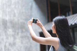 mujer asiática viajera que usa un teléfono móvil para tomar una foto mientras pasa un viaje de vacaciones en beijing, china, la mujer disfruta de un viaje en un punto de referencia increíble en la ciudad. las mujeres de estilo de vida viajan en concepto de ciudad.