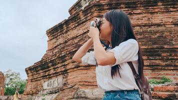 mujer asiática viajera que usa la cámara para tomar una foto mientras pasa un viaje de vacaciones en ayutthaya, tailandia, la turista japonesa disfruta de su viaje en un hito increíble en la ciudad tradicional.