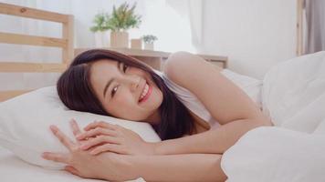 Asian woman smiling lying on bed in bedroom, Beautiful japanese female using relax time after wake up at home. Lifestyle women using relax time at home concept. photo