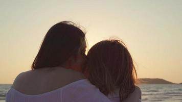 Young Asian lesbian couple kissing near beach. Beautiful women lgbt couple happy relax enjoy love and romantic moment when sunset in evening. Lifestyle lesbian couple travel on beach concept. photo