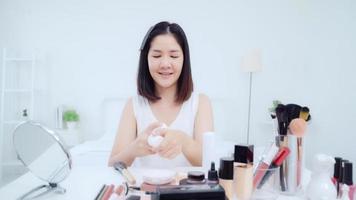 Beauty blogger present beauty cosmetics sitting in front camera for recording video. Happy beautiful young Asian woman use cosmetics review make up tutorial broadcast live video to social network. photo
